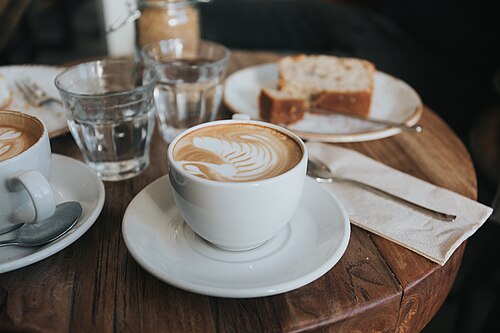 Cappuccinos and a slice of cake on a café table (CC0, Alisa Anton)