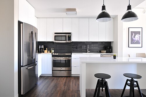 A white kitchen with black pendant lights (CC0, Naomi Hébert)